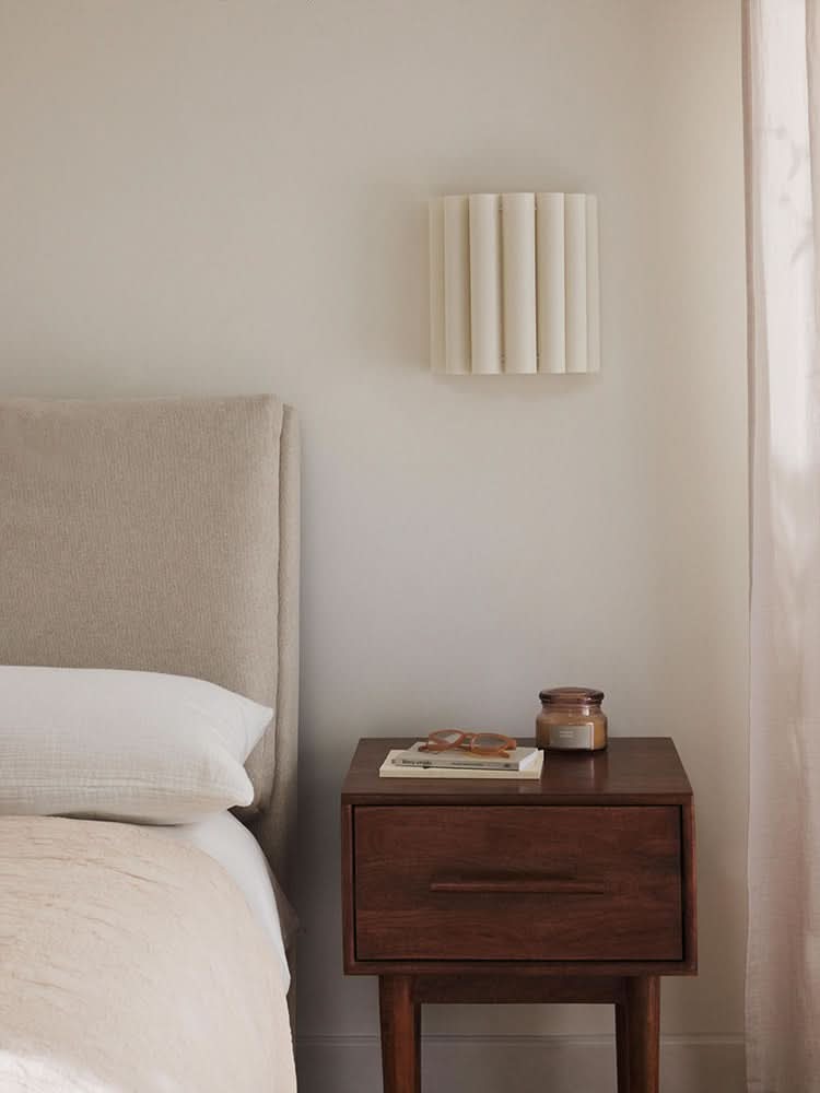 Modern Pleated Fabric Pendant Light in cream, mounted above a nightstand in a bedroom.